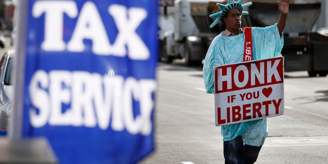 Jan. 22, 2013: Dressed as the Statue of Liberty, part-time employee, Zidkijah Zabad, waves to passing motorists while holding a sign to advertise for Liberty Tax Service in Los Angeles.