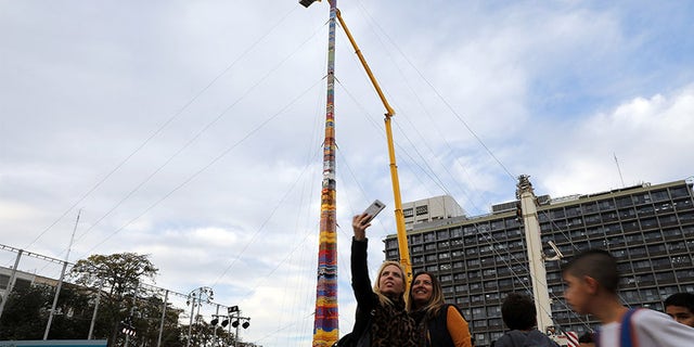 Women pose for a selfie next to a Lego tower that measures 118 feet.