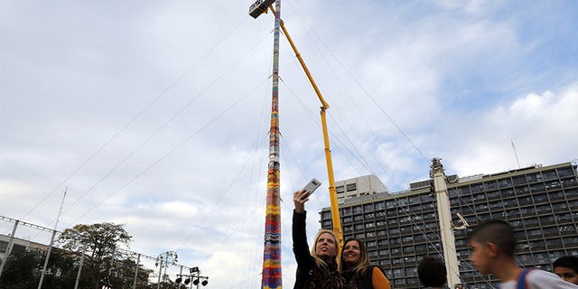 Women pose for a selfie next to a Lego tower that measures 118 feet.