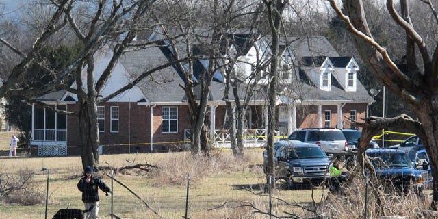 February 11, 2014: An officer and a dog inspect a fence near a home in Lebanon, Tenn. where police said a package exploded, killing a 74-year-old man and injuring a woman. (AP Photo/Lucas L. Johnson II)