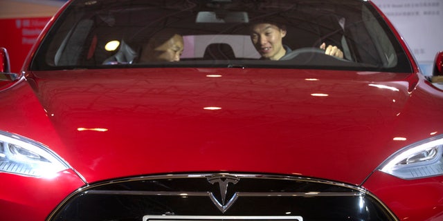FILE - In this Monday, April 25, 2016, file photo, a man sits behind the steering wheel of a Tesla Model S electric car on display at the Beijing International Automotive Exhibition in Beijing. Tesla said Thursday, June 9, 2016, that it has started selling a cheaper version of its Model S car in an attempt to make its electric vehicles more affordable for more people. The new version, called the Model S 60, starts at $66,000. An all-wheel drive version of the Model S 60 will start at $71,000. Both cost less that the current Model S 90D, which starts at $89,500. (AP Photo/Mark Schiefelbein, File)