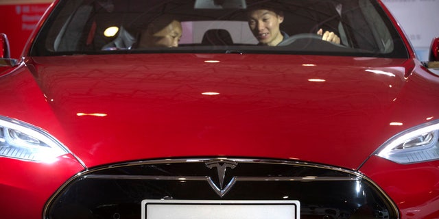 FILE - In this Monday, April 25, 2016, file photo, a man sits behind the steering wheel of a Tesla Model S electric car on display at the Beijing International Automotive Exhibition in Beijing. Tesla said Thursday, June 9, 2016, that it has started selling a cheaper version of its Model S car in an attempt to make its electric vehicles more affordable for more people. The new version, called the Model S 60, starts at $66,000. An all-wheel drive version of the Model S 60 will start at $71,000. Both cost less that the current Model S 90D, which starts at $89,500. (AP Photo/Mark Schiefelbein, File)