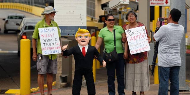 FILE - In this July 31, 2015 file photo, two women pose for a photo standing next to a pinata in the likeness of Donald Trump, during a protest against Trump and derogatory remarks he has made about Mexicans, in Brownsville, Texas. Mexico’s ambassador-designate to Washington, Miguel Basanez, sought to downplay Trump’s comments on Mexico, telling a Senate confirmation hearing on Friday, Aug. 28, 2015, that Trump is simply playing politics. (Brad Doherty/The Brownsville Herald via AP) MANDATORY CREDIT