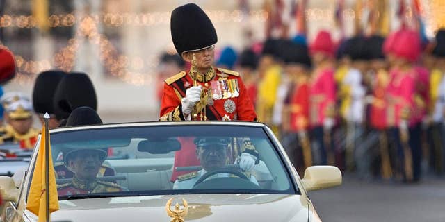 FILE - In this Dec. 2, 2008 file photo, Thailand's King Bhumibol Adulyadej reviews the honor guard in Bangkok, Thailand. Prosecutors in Thailand have charged two people with defaming the country's monarchy in a stage performance at a university last year, moving on a complaint filed by a group of royalists, a lawyer said Tuesday, Oct. 28, 2014. (AP Photo/David Longstreath, File)