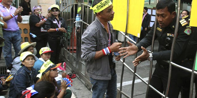 January 26, 2014: Anti-government protester talk to an election officer while gathering in front of a polling station in Patumwan district during a rally in Bangkok, Thailand. (AP Photo/Sakchai Lalit)