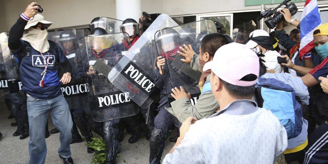 December 25, 2013: Thai anti-government protesters scuffle with riot policemen in an attempt to disrupt the election registration at a sport gymnasium in Bangkok. Thai Prime Minister Yingluck Shinawatra on Wednesday proposed the formation of a national reform council tasked with finding solutions to the political turmoil that is splitting the country and paralyzing governance. (AP Photo/Apichart Weerawong)