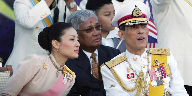 FILE - In this Aug. 31, 2007 file photo, Thailand's Crown Prince Vajiralongkorn, right, chats with his royal consort Princess Srirasm as they watch a parade at the historic Merdeka square in downtown Kuala Lumpur,  Malaysia. Thailand's Crown Prince Vajiralongkorn has asked the government to strip his wife's family of their royally issued surname, the latest development in a high-profile crackdown that involves senior members of the police force. The move came after at least three of Princess Srirasm's relatives were arrested as part of the probe. In a letter dated Friday, Nov. 28, 2014 but released over the weekend, the crown prince ordered the "cancellation of the royally bestowed family name 'Akrapongpreecha,'" which was issued after the pair married in 2001. (AP Photo/Vincent Thian, File)
