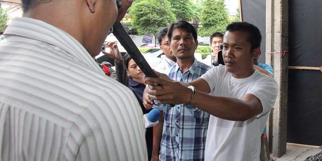 July 7, 2013 - Chidchai Utmacha, right, a Thai taxi driver shows how he stabbed an American passenger, Troy Lee Pilkington, during a police re-enactment in Bangkok, Thailand. Thai police arrested Chidchai accused of stabbing Pilkington to death in an argument over a fare worth less than $2.