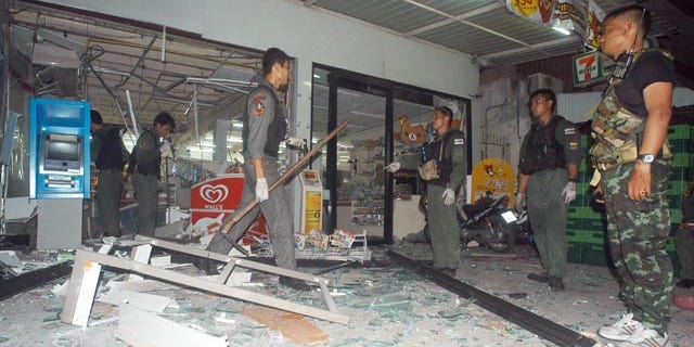 May 24, 2014: Thai police officers and soldiers examine the site where a bomb exploded at a super store in Pattani province, southern Thailand. (AP Photo/Sumeth Panpetch)