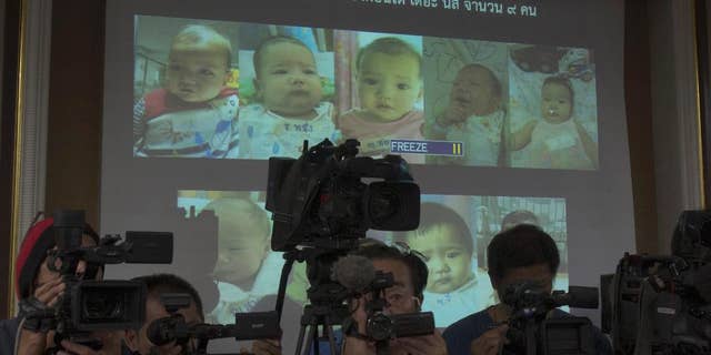 FILE - In this Tuesday, Aug. 12, 2014 file photo, Thai police display pictures of surrogate babies born to a Japanese man who is at the center of a surrogacy scandal during a press conference at the police headquarters in Chonburi, Thailand. A string of recent scandals has lifted a lid on Thailand's largely unregulated commercial surrogacy industry, which has been around for over a decade. (AP Photo/Sakchai Lalit)