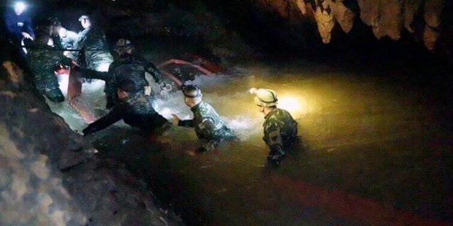 Thai rescue teams use headlamps to enter a pitch-black cave complex where 12 boys and their soccer coach went missing, in Mae Sai, Chiang Rai province, northern Thailand, Monday, July 2, 2018.