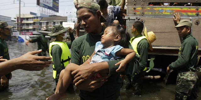 Oct. 21, 2011: A Thai soldier carries a girl down a truck as they evacuate to higher grounds at the flooded district of Rangsit on the outskirts of Bangkok, Thailand.