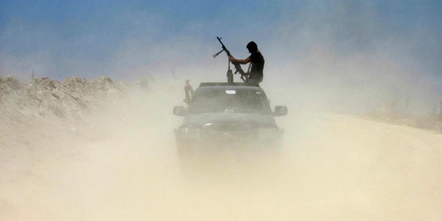 FILE - A fighter with Badr Brigades an armed Shiite group under the umbrella of the Popular Mobilization Forces loads his rifle as Iraqi security forces and allied Shiite Popular Mobilization Forces and Sunni tribal fighters, take combat positions outside Fallujah, 40 miles (65 kilometers) west of Baghdad, Iraq, Monday, May 23, 2016. Iraqi government forces on Monday pushed Islamic State militants out of some agricultural areas outside Fallujah as they launched a military offensive to recapture the city from the extremists, officials said. (AP Photo/Rwa Faisal)