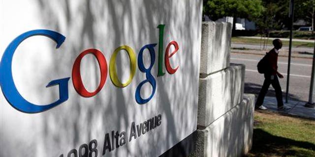 In this June 5, 2014, photo, a man walks past a Google sign at the company's headquarters in Mountain View, Calif.