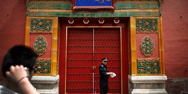 A tourist looks at a policeman stand in front of the entrance doorway to the Palace Museum, which announced the find.