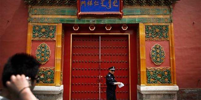 A tourist looks at a policeman stand in front of the entrance doorway to the Palace Museum, which announced the find.