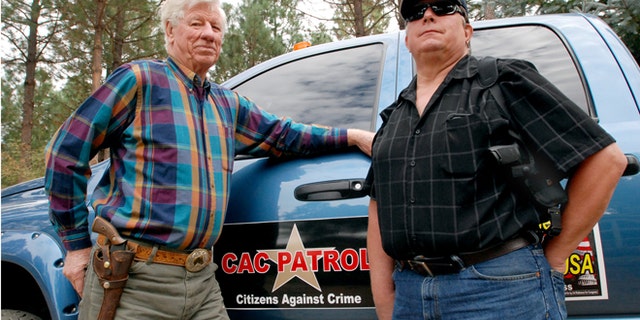 Oct. 12: Sam Nichols, left, and Glenn Woodbury pose in front of Woodbury's pickup in O'Brien, Ore. The two men are part of a neighborhood watch that does armed patrols around the rural area to deter crime since budget cutbacks have left the Josephine County Sheriff's Office with just three patrol deputies and limited jail space.