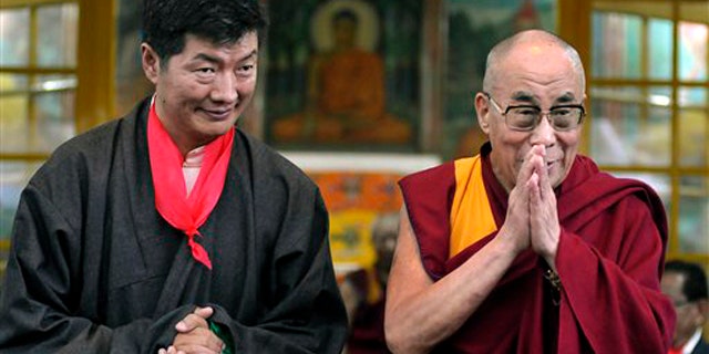 Lobsang Sangay, left, the new prime minister of Tibet's government in exile, stands next to Tibetan spiritual leader the Dalai Lama as he greets the crowd at his swearing-in ceremony at the Tsuglakhang Temple in Dharmsala, India, Monday, Aug. 8, 2011.
