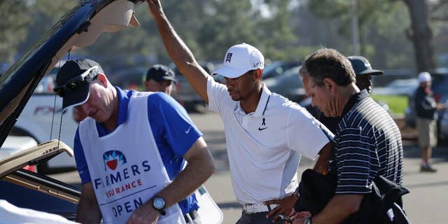 FILE - In this Feb. 5, 2015, file photo, Tiger Woods, center, loads his car after withdrawing during the first round of the Farmers Insurance Open golf tournament in San Diego. Woods was fleeing from a golf tournament in mid-round, mumbling something about improper activation of his glutes. Two weeks before the Masters he's still missing in action, though his fans have plenty of ideas on how to get his mojo back. (AP Photo/Gregory Bull, File)