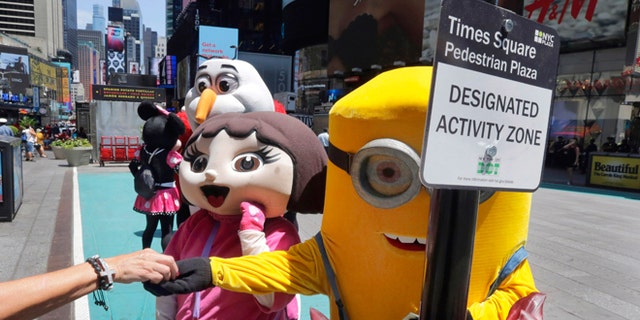 Costumed characters work in New York's Times Square, Tuesday, June 21, 2016.
