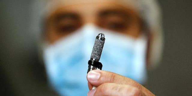 An Italian heart surgeon holds a tiny titanium pump, the world's smallest artificial heart, which was implanted in a baby, at the Bambino Gesu' Hospital in Rome
