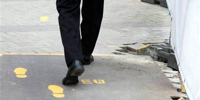 A man follows a yellow foot path in Brussels, Wednesday, June 27, 2012.