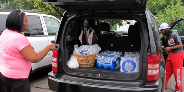 August 2, 2014: Aundrea Simmons stands next to her minivan with cases of bottled water she bought after Toledo warned residents not to use its water. About 400,000 people in and around Ohio's fourth-largest city were warned not to drink or use its water after tests revealed the presence of a toxin possibly from algae on Lake Erie. (AP Photo/John Seewer)