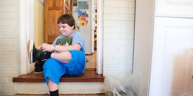 Sunnie Kahle, 8, puts on her shoes before leaving her home in Forest, Va. on March 26, 2014. Kahle recently withdrew from Timberlake Christian School in Forest, Va. after the school sent a letter asking her to either dress and act more feminine or not enroll again because she looked too much like a boy. (AP Photo/The News & Advance, Jill Nance)