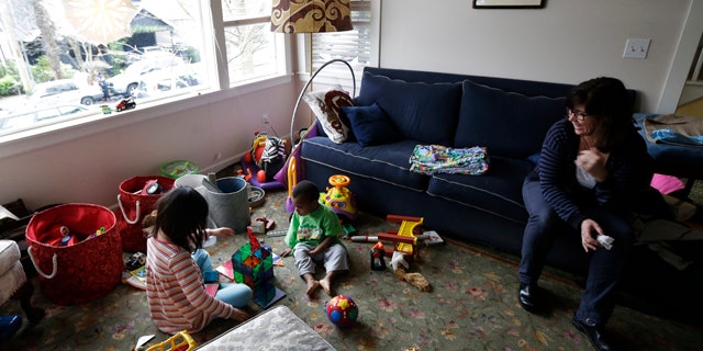 Feb. 12, 2013: Nancy Jensen, right, watches as her children, Elizabeth, 6, left, and Joe, 2, center, play with a building set and other toys.