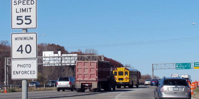 Nov. 12, 2013, file photo, of vehicles passing a highway sign along Interstate 380 in Cedar Rapids, Iowa, warning drivers that the 55-mph speed limit is enforced by speed cameras.