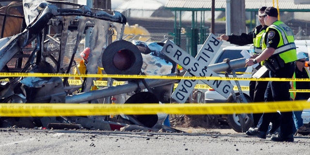 In this Tuesday, Feb. 24, 2015, photo Police officers stand near a Metrolink train that hit a truck, leftt, and then derailed at a railroad crossing in Oxnard, Calif. Three cars of the Metrolink train tumbled onto their sides, injuring dozens of people in the town 65 miles northwest of Los Angeles. Engineers have figured how to blunt the deadly force of a train smashing into a truck on the tracks. Yet few U.S. rail systems have adopted the technology, which is believed to have played a significant role in the remarkably low number of serious injuries from Tuesdays commuter rail crash. (AP Photo/Mark J. Terrill)