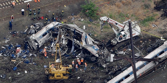 In this aerial photo taken May 13, 2015, emergency personnel work at the scene of a deadly train wreck in Philadelphia. Amtrak faces what probably will be a $200 million payout to crash victims _ the cap established by Congress nearly 20 years ago as part of a compromise to rescue the railroad from financial ruin. It would be the first time that the liability ceiling, considered by many to be too low to cover the costs of the eight lives lost and 200 people injured, designed for Amtrak actually would apply to the railroad. (AP Photo/Patrick Semansky)