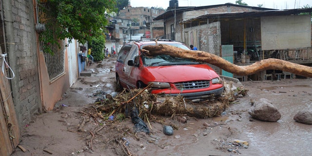 A damaged vehicle stands in the middle of a road after a landslide caused by heavy rains came down on a low income neighborhood in the city of Chilpancingo, Mexico, Monday Sept. 16, 2013. Tropical Storm Ingrid and remnants of Tropical Storm Manuel drench Mexico's Gulf and Pacific coasts, flooding towns and cities in a national emergency that federal authorities say has caused at least 34 deaths. (AP Photo/Alejandrino Gonzalez)