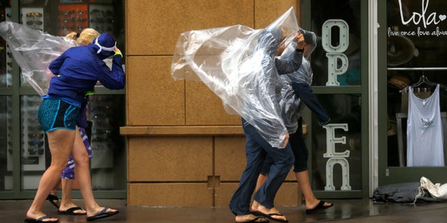Pedestrians brave the wind rushing down Atlantic Ave. in Virginia Beach, Va., on Saturday, Sept. 3, 2016, as Tropical Storm Hermine approaches the region. The National Hurricane Center says Tropical Storm Hermine could bring 4 to 7 inches of rain to southeastern Virginia and the Atlantic coastal portion of Maryland as well as 1 to 4 inches of rain over southern Delaware, southern and eastern New Jersey and Long Island through Monday morning. (Stephen M. Katz/The Virginian-Pilot via AP)