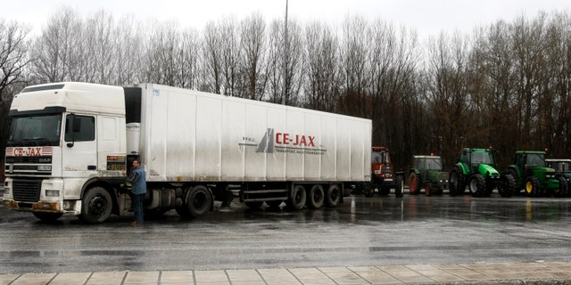 A truck driver stands next to tractors blocking the Promahonas border crossing to Bulgaria in northern Greece January 28, 2009. Thousands of farmers demanding compensation for low prices blocked highways across Greece for a tenth day, hampering the transport of medicine and keeping the Bulgarian border shut despite protests from Sofia. REUTERS/Yiorgos Karahalis (GREECE)