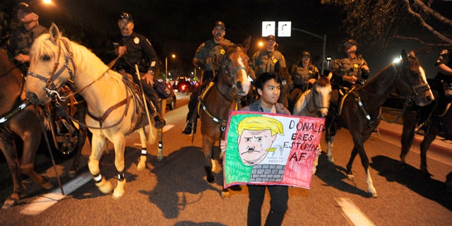 Police on horseback and on foot clear the anti-Trump demonstrators on Thursday, April 28, 2016, in Costa Mesa, Calif.