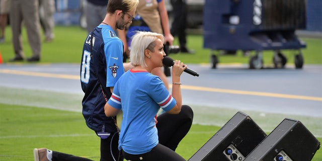 Recording artist Meghan Linsey kneels agter singing the national anthem