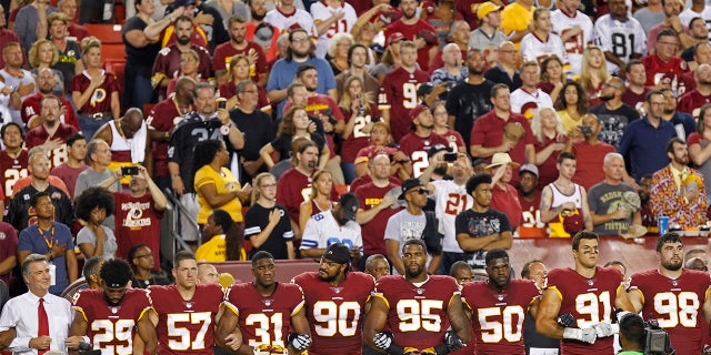 Sep 24, 2017; Landover, MD, USA; Washington Redskins president Bruce Allen (L) stands with Redskins players arm in arm during the national anthem prior to their game against the Oakland Raiders at FedEx Field. Mandatory Credit: Geoff Burke-USA TODAY Sports - 10305314
