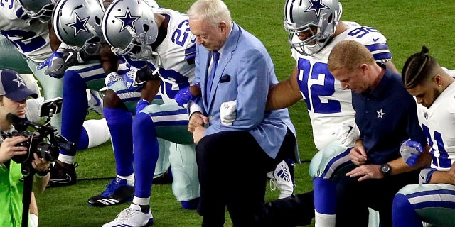 The Dallas Cowboys, led by owner Jerry Jones, center, take a knee prior to the national anthem