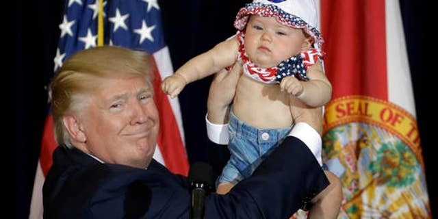 Republican presidential candidate Donald Trump holds up 6-month-old Catalina Larkin, of Largo, Fla., during a campaign rally Saturday, Nov. 5, 2016, in Tampa, Fla. (AP Photo/Chris O'Meara)