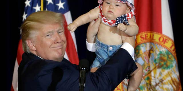 Republican presidential candidate Donald Trump holds up 6-month-old Catalina Larkin, of Largo, Fla., during a campaign rally Saturday, Nov. 5, 2016, in Tampa, Fla. (AP Photo/Chris O'Meara)