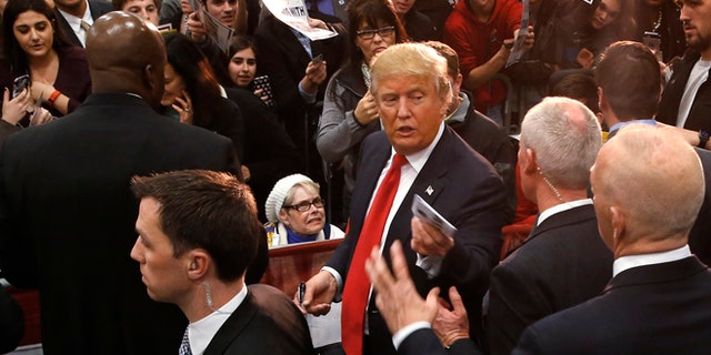 Republican presidential candidate Donald Trump hands a memento to staff during a campaign event at the University of Iowa Field House, Tuesday, Jan. 26, 2016 in Iowa City, Iowa. (AP Photo/Paul Sancya)
