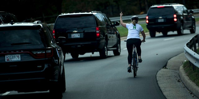 Juli Briskman gestures with her middle finger as a motorcade with US President Donald Trump departs Trump National Golf Course October 28, 2017 in Sterling, Virginia.