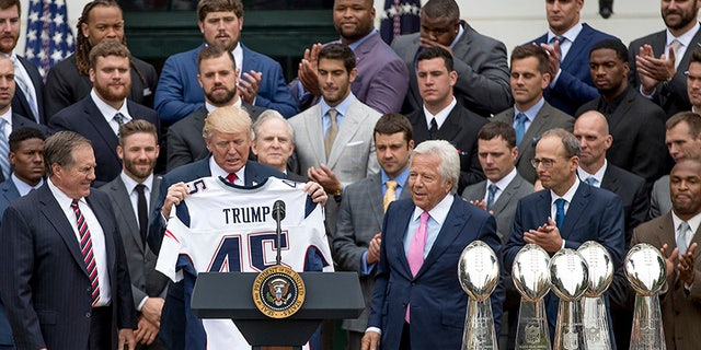 President Donald Trump is presented with a New England Patriots jersey by Patriots head coach Bill Belichick, left, and New England Patriots owner Robert Kraft, center, during a ceremony on the South Lawn of the White House in Washington, Wednesday, April 19, 2017, where the president honored the Super Bowl Champion New England Patriots for their Super Bowl LI victory. Also pictured is New England Patriots president Jonathan Kraft, second from right. (AP Photo/Andrew Harnik)