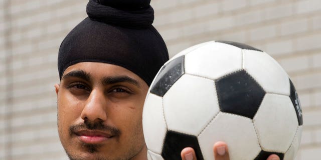 In this photo taken Wednesday, June 5, 2013, Aneel Samra, 18, holds a soccer ball in his backyard as he poses for a photo in Montreal. Samra said he's perplexed by the Quebec Soccer Federation's decision to uphold a year-old ban on Sikh turbans, patkas and keskis, without any evidence they pose a safety risk.  (AP Photo/The Canadian Press, Ryan Remiorz)
