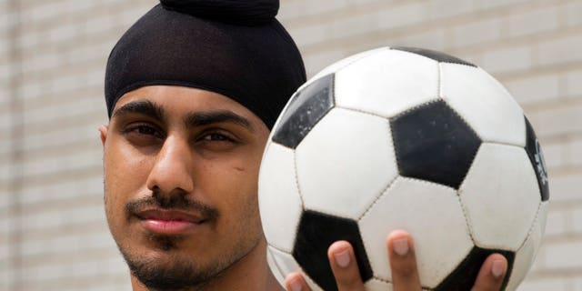 In this photo taken Wednesday, June 5, 2013, Aneel Samra, 18, holds a soccer ball in his backyard as he poses for a photo in Montreal. Samra said he's perplexed by the Quebec Soccer Federation's decision to uphold a year-old ban on Sikh turbans, patkas and keskis, without any evidence they pose a safety risk. (AP Photo/The Canadian Press, Ryan Remiorz)