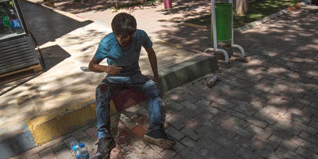 July 20, 2015: A youth wounded in an explosion that killed dozens of people and injured scores of others sits in the Turkish town of Suruc near the Syrian border (AP Photo/Zeki Yavuzak)