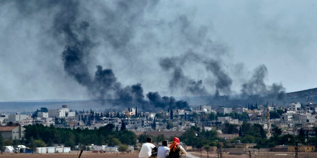 Oct. 26, 2014 - Syrian Kurdish refugees from Kobani watch fighting across the border in Kobani from the outskirts of Suruc, Turkey, near the Turkey-Syria border. A new UN report says the world is facing a challenge of foreign fighters in terror groups on an "unprecedented scale," with about 15,000 in Syria and Iraq alone.