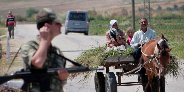 A Turkish family rides on a cart near Turkish soldiers guarding a Syrian refugee a camp, during a brief visit organized by Turkish authorities for the media, in Boynuyogun, Turkey, Saturday, June 18, 2011. According to Turkish authorities more than 10,000 Syrians are now in refugee camps in the Hatay province, near Turkey's border with Syria.