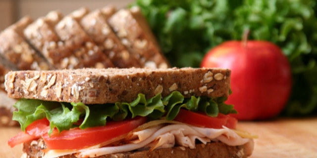 Healthy sandwhich made with whole grain bread, lettuce, tomato, cheese, and roasted chicken slices.